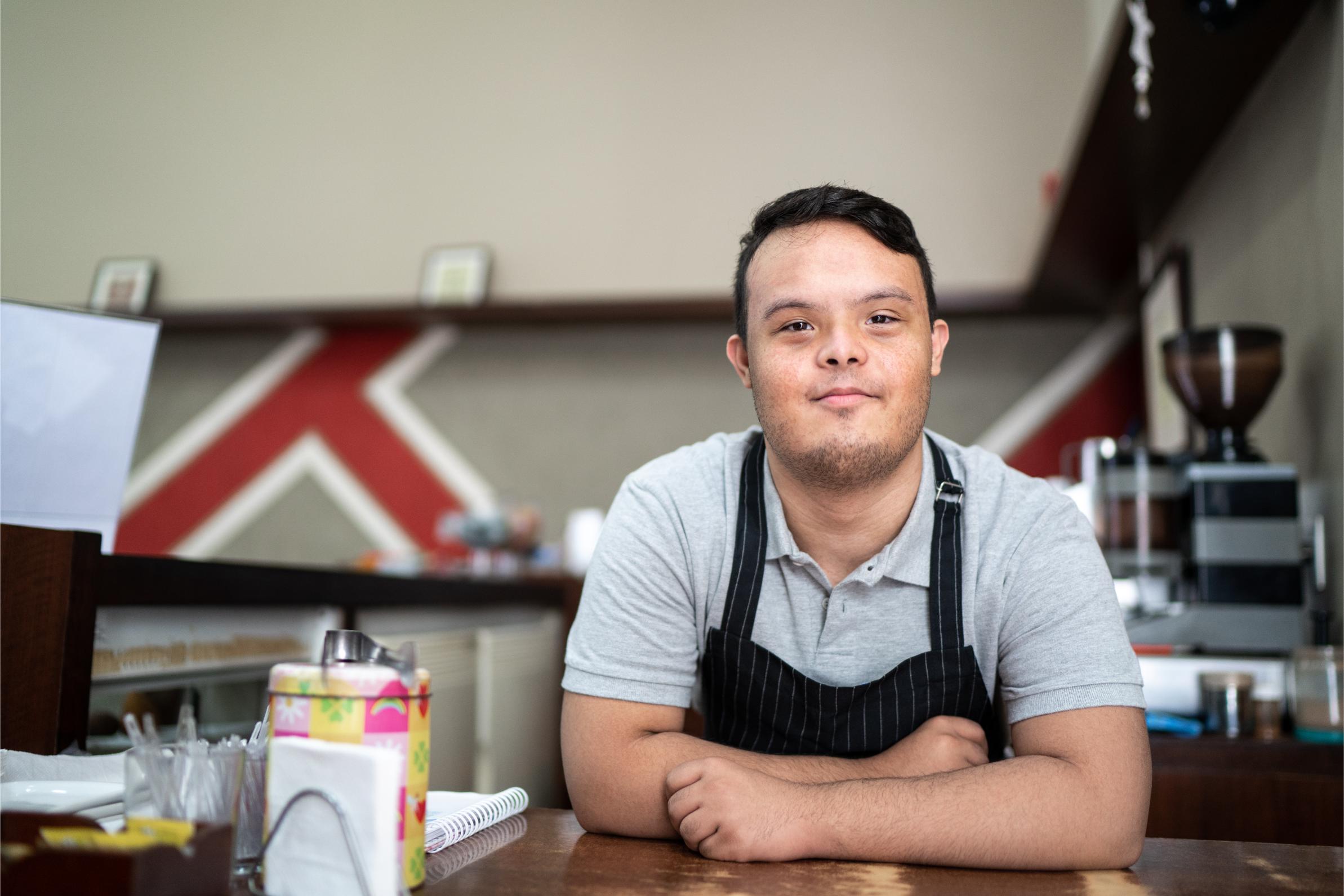 man with developmental disability posing for photo at job in cafe